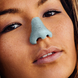 Close up of woman wearing colorful Nöz sunscreen in teal blue.